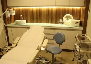 Sala de procedimentos da clínica com maca, cadeira e bancada