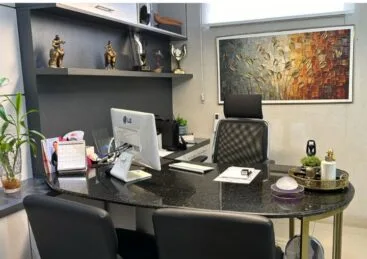 Consultório da clínica com mesa de atendimento e cadeiras para consulta